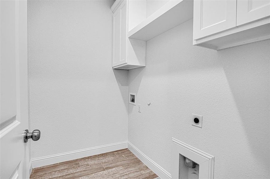 Laundry area featuring cabinet space, electric dryer hookup, light wood-type flooring, baseboards, and hookup for a gas dryer Laundry area featuring cabinet space, electric dryer hookup, light wood-type flooring, baseboards, and hookup for a gas dryer