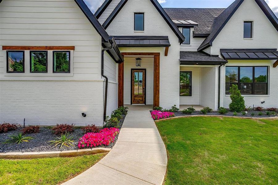 View of front facade featuring a standing seam roof, brick siding, and a front yard View of front facade featuring a standing seam roof, brick siding, and a front yard