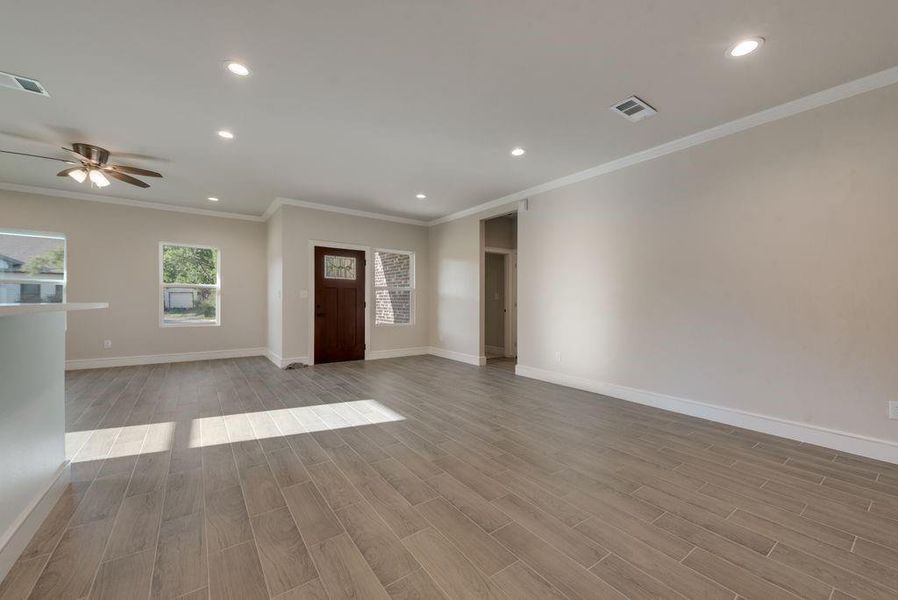 Unfurnished living room featuring light hardwood / wood-style floors, crown molding, and ceiling fan