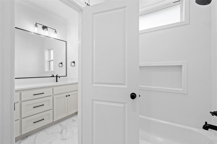 Full bath featuring light marble finish flooring, vanity, and a bathtub Full bath featuring light marble finish flooring, vanity, and a bathtub