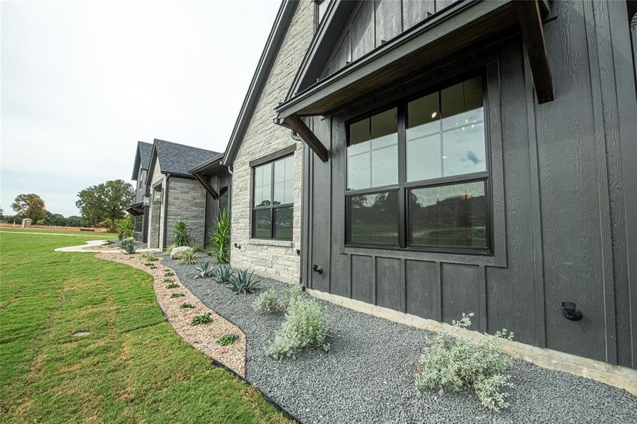 View of side of home with stone siding, board and batten siding, and a yard View of side of home with stone siding, board and batten siding, and a yard
