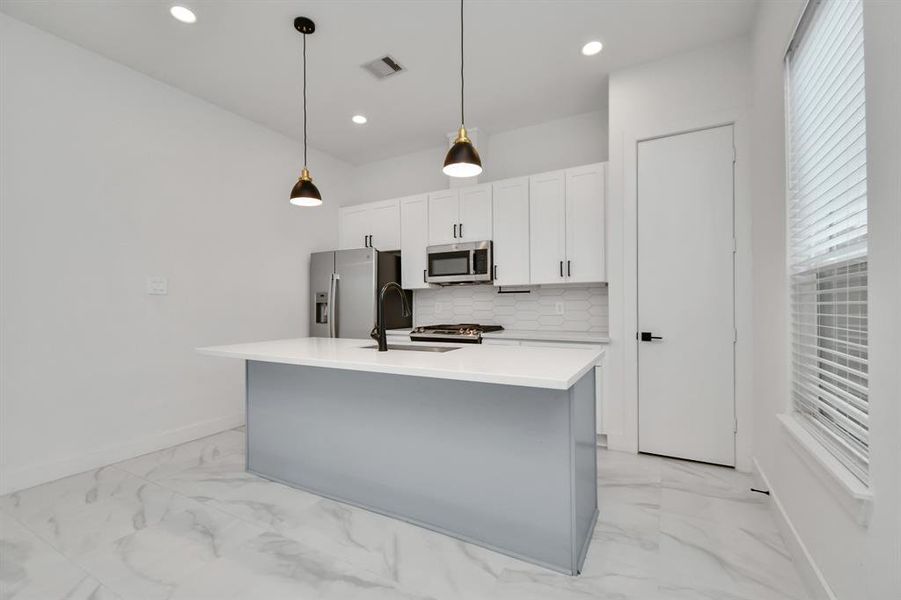 Delight in meal prep or host elegant dinner parties in this tastefully appointed open concept kitchen dining area, enhanced by the soft glow of recessed lighting and elegant light fixtures