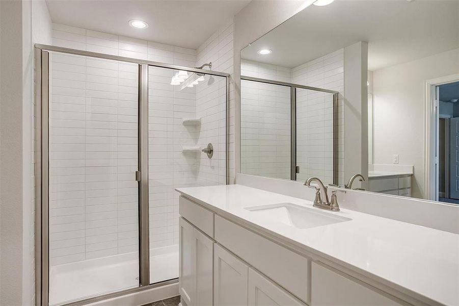 Bathroom with a stall shower, vanity, and recessed lighting