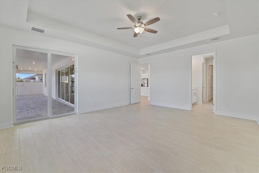 Unfurnished room featuring a tray ceiling, ceiling fan, and wood finish floors Unfurnished room featuring a tray ceiling, ceiling fan, and wood finish floors