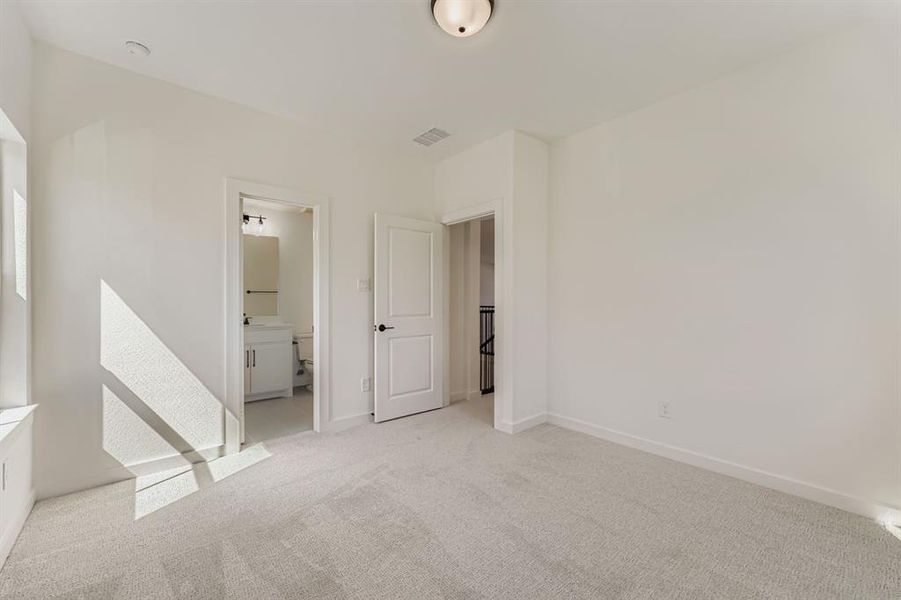 Unfurnished bedroom with carpet floors and ensuite bath