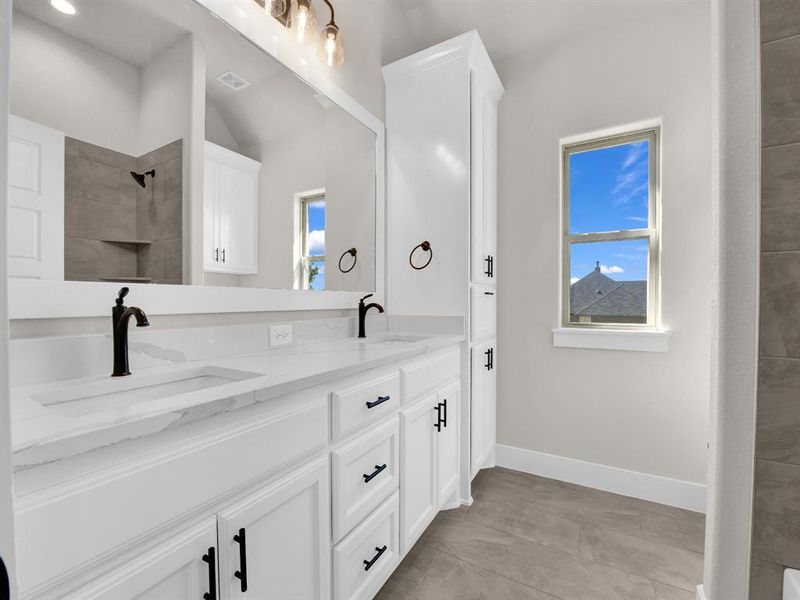 Bathroom with double vanity and tiled shower