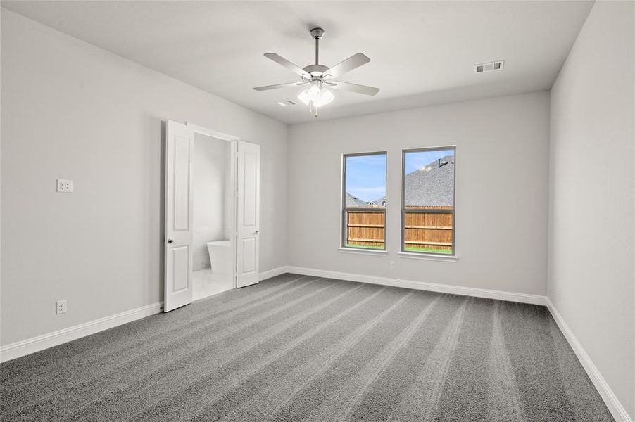Unfurnished bedroom with dark carpet, baseboards, ensuite bathroom, and ceiling fan Unfurnished bedroom with dark carpet, baseboards, ensuite bathroom, and ceiling fan