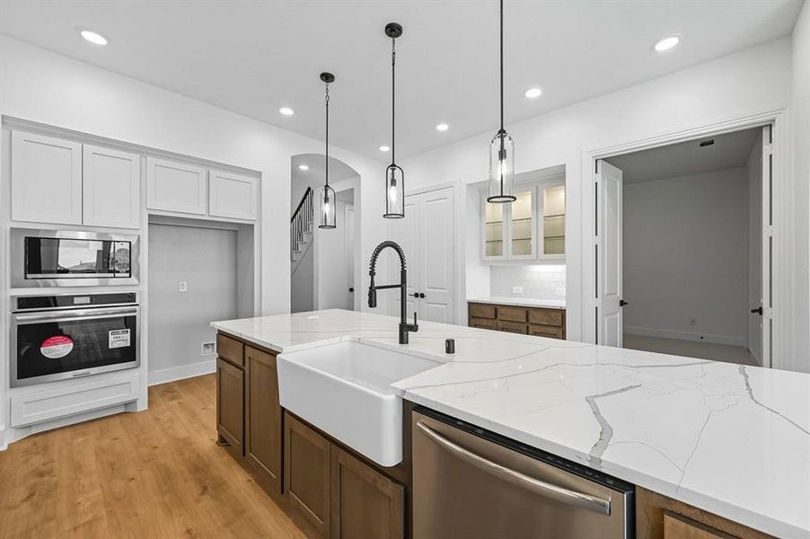 Kitchen with stainless steel appliances, light wood-type flooring, light stone countertops, white cabinetry, and recessed lighting Kitchen with stainless steel appliances, light wood-type flooring, light stone countertops, white cabinetry, and recessed lighting