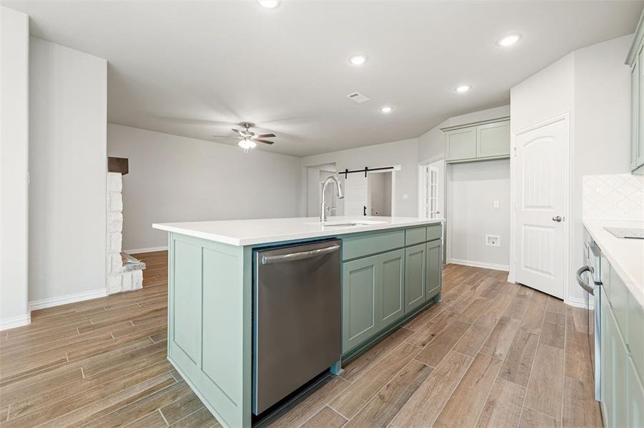 Kitchen featuring green cabinetry, recessed lighting, appliances with stainless steel finishes, wood tiled floors, and an island with sink Kitchen featuring green cabinetry, recessed lighting, appliances with stainless steel finishes, wood tiled floors, and an island with sink