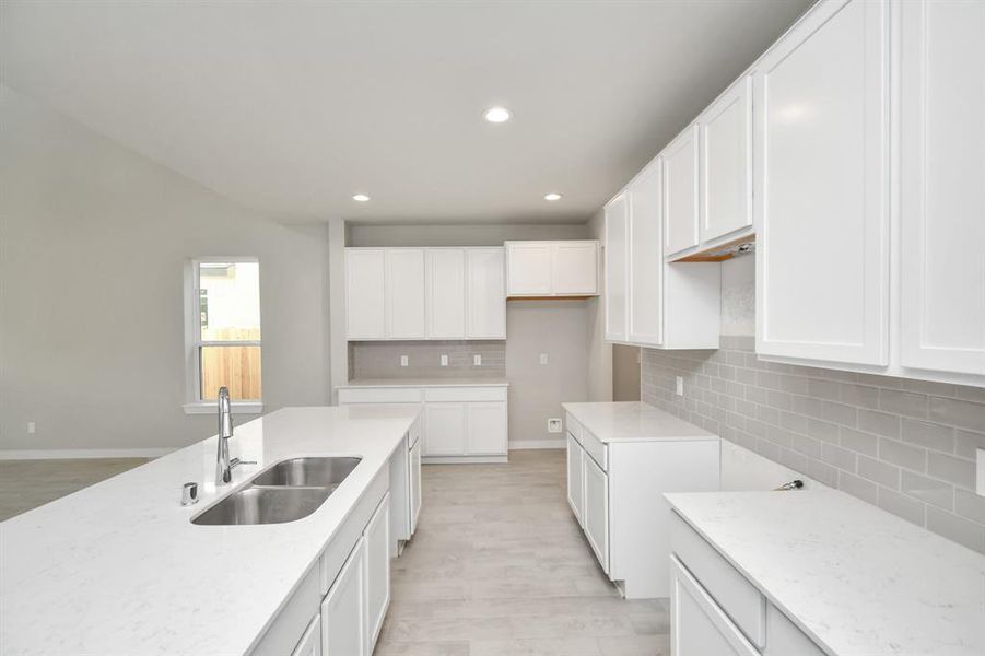 Culinary haven, featuring granite countertops, a tile backsplash, stainless steel appliances, 42” upper cabinets, and bright recessed lighting. Sample photo of completed home with similar floor plan. As-built interior colors and selections may vary.