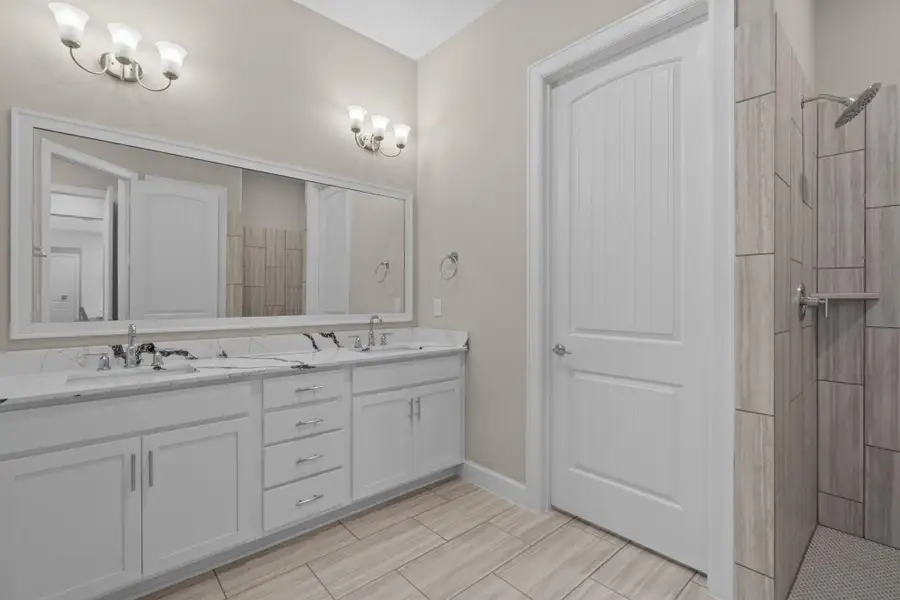 The Promenade III primary bathroom offers a spa-inspired retreat with dual vanities, a walk-in shower, and elegant finishes designed for daily comfort and style. Image depicts home as-is.