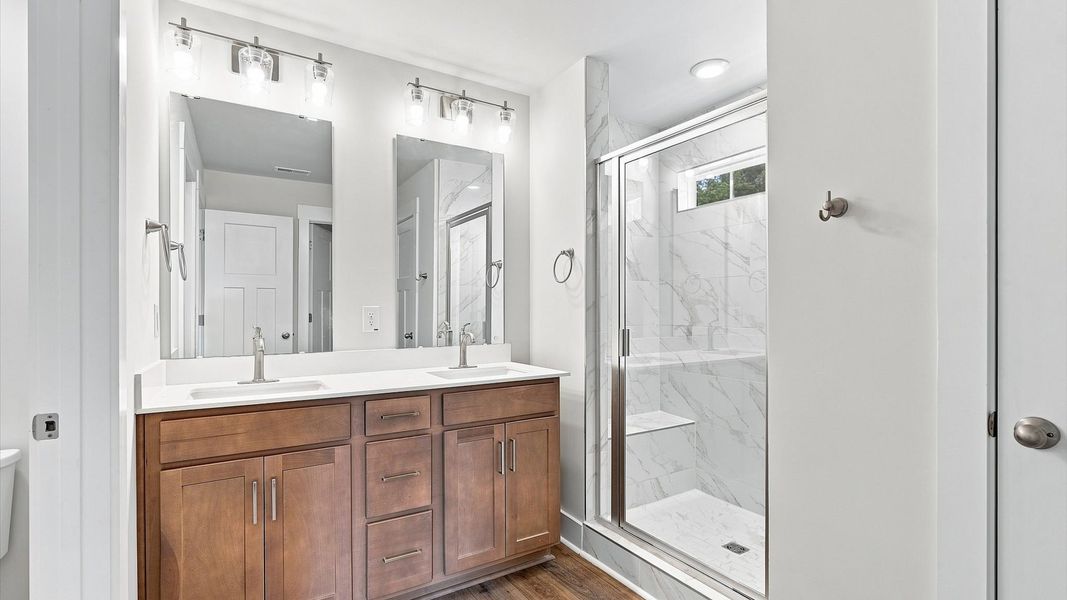 Superior en-suite primary bathroom with stylish dual vanity and tiled walk-in shower crafted with high standards in mind