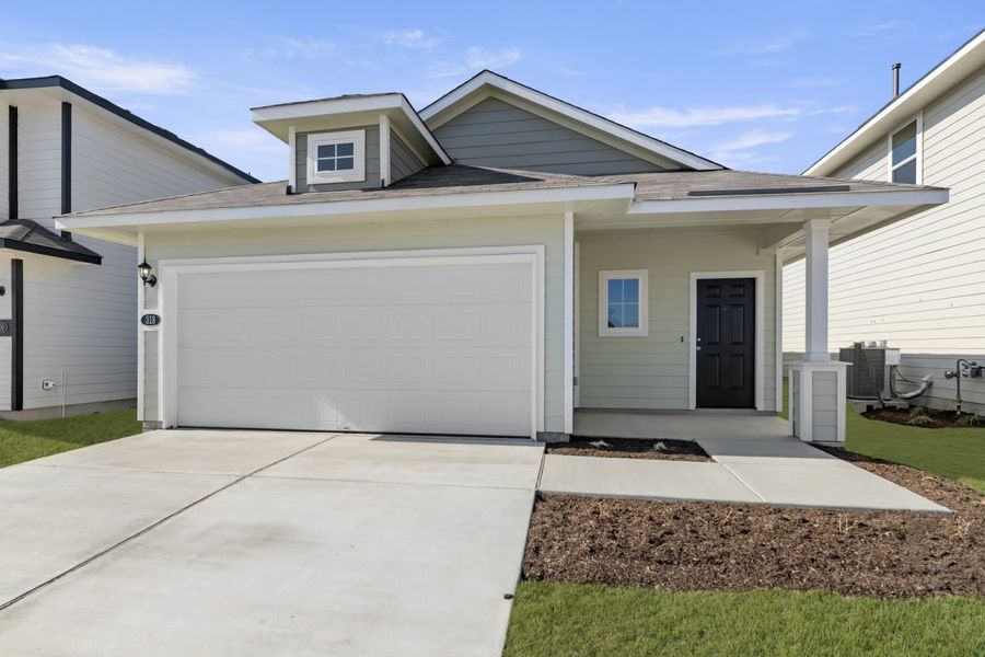 Image of a light green one story house with a white garage door, a black front door, a cement driveway, and a blue sky in the background Image of a light green one story house with a white garage door, a black front door, a cement driveway, and a blue sky in the background