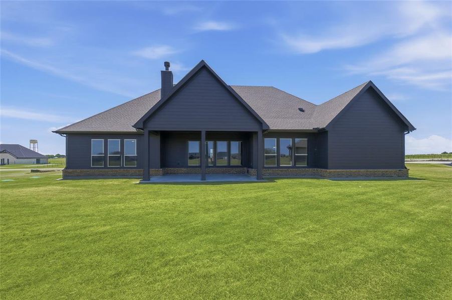 Expansive backyard featuring a covered patio, dark siding, and a stone-clad foundation Expansive backyard featuring a covered patio, dark siding, and a stone-clad foundation