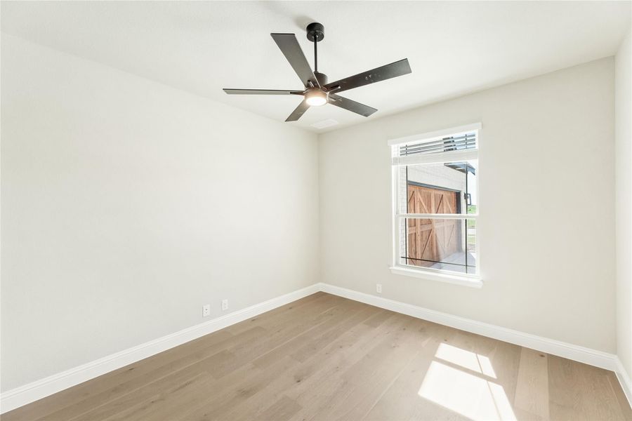 Empty room with light wood floors, white walls, ceiling fan, and single window Empty room with light wood floors, white walls, ceiling fan, and single window