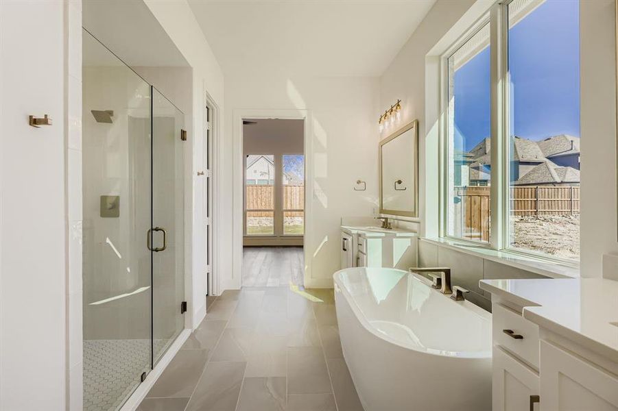 Bathroom featuring vanity, a freestanding bath, a shower stall, and light tile patterned floors Bathroom featuring vanity, a freestanding bath, a shower stall, and light tile patterned floors