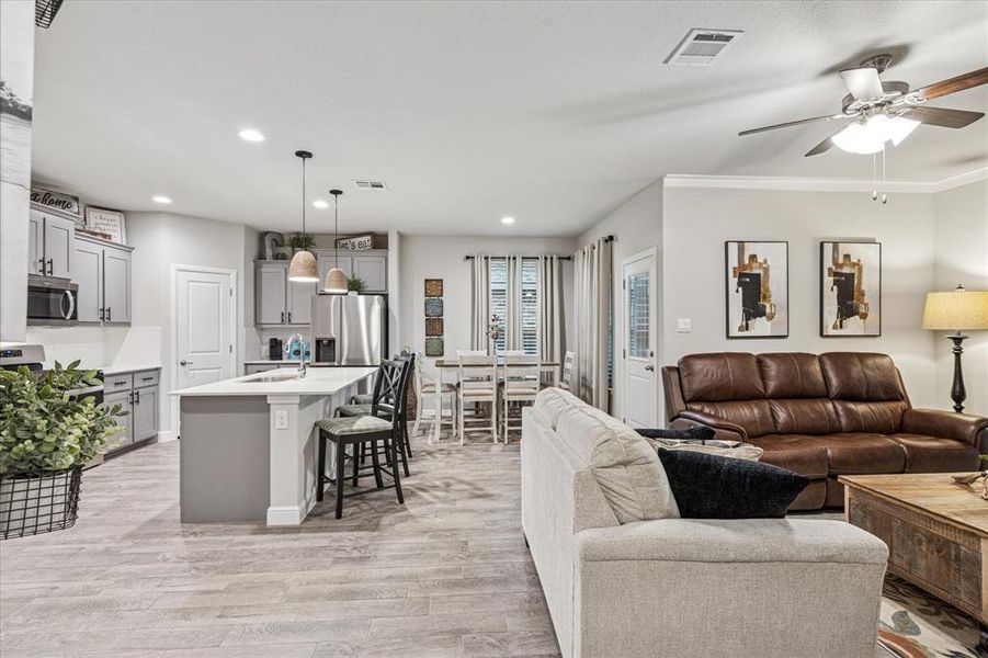 Living room featuring light wood-style flooring, ceiling fan, recessed lighting, and crown molding Living room featuring light wood-style flooring, ceiling fan, recessed lighting, and crown molding