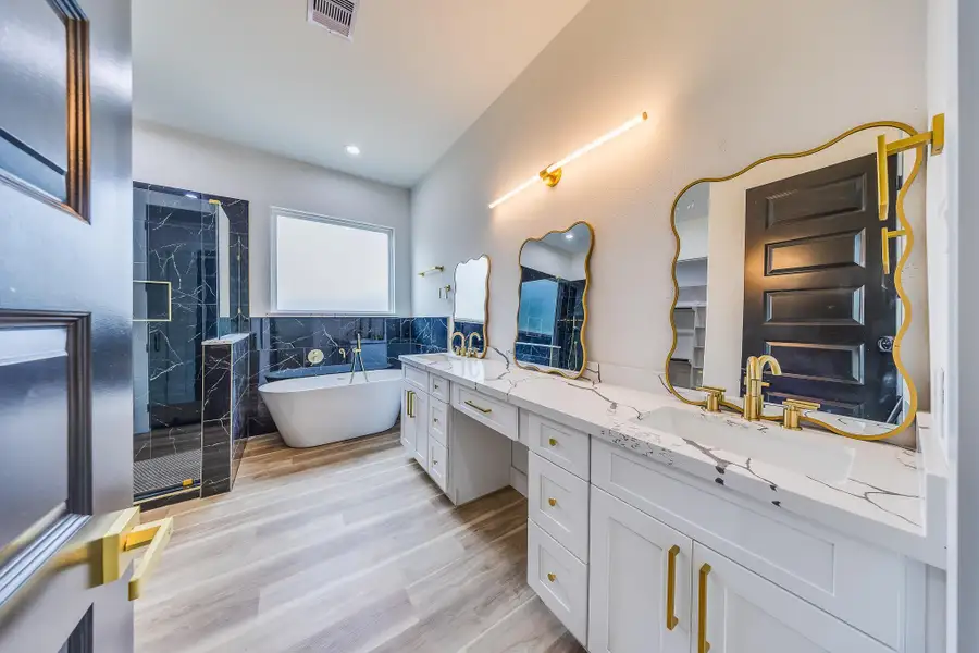 A spa-inspired master bath with elegant design, soaking tub, gold fixtures, and a separate shower. A spa-inspired master bath with elegant design, soaking tub, gold fixtures, and a separate shower.