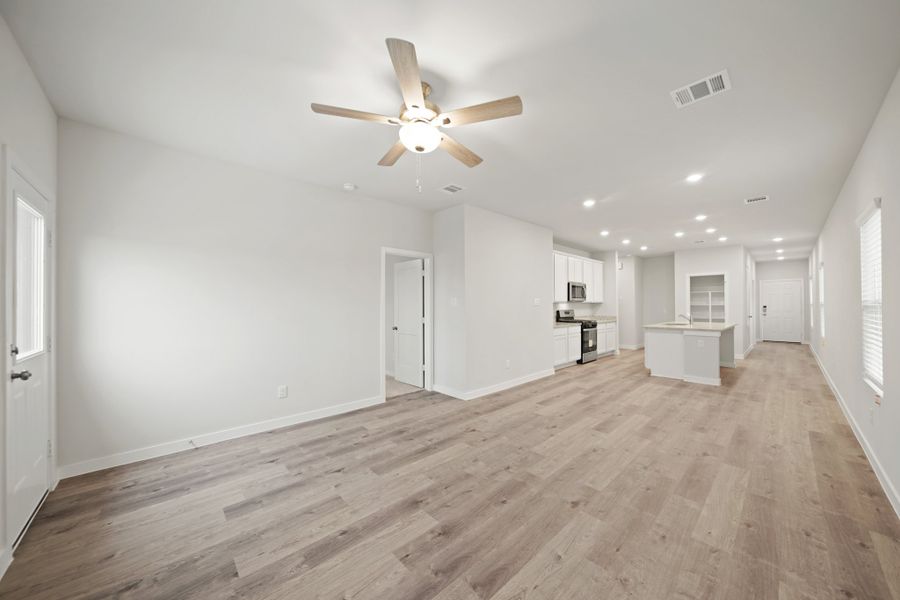 A large empty room with a ceiling fan and wood floors.