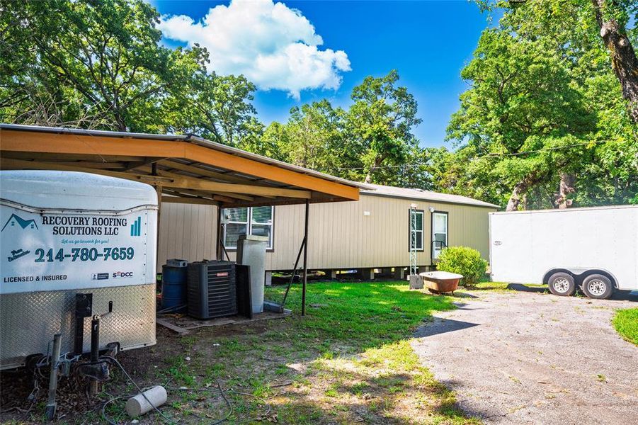 View of side of property with a central air condition unit and a carport