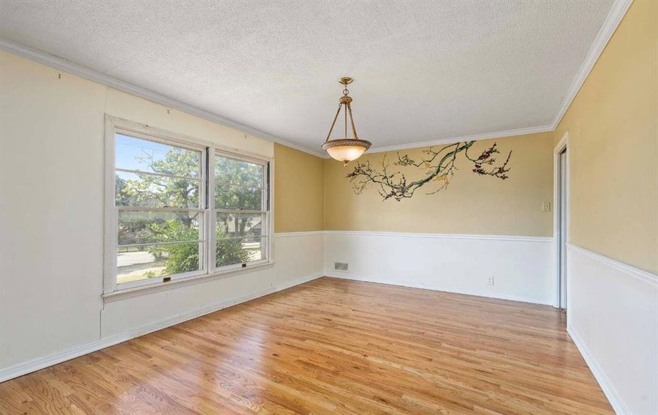 Unfurnished room featuring light wood-type flooring, a textured ceiling, and crown molding