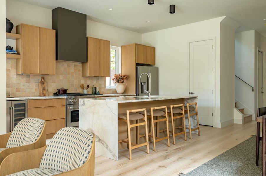 A spacious waterfall island centers this modern kitchen lined with light oak cabinetry. A spacious waterfall island centers this modern kitchen lined with light oak cabinetry.