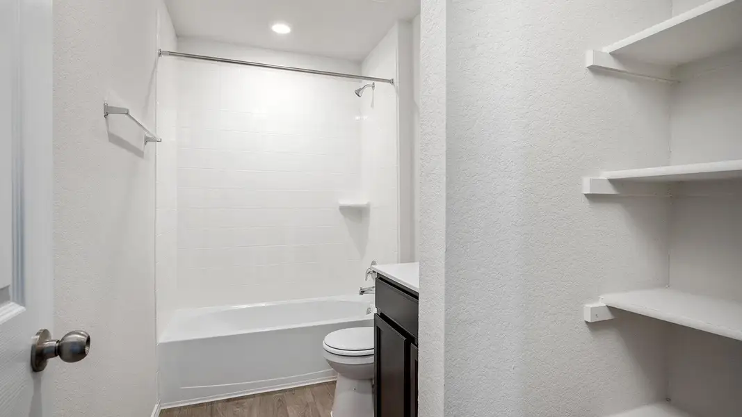 Bathroom featuring vanity, a textured wall, shower / bathtub combination, and light wood-type flooring