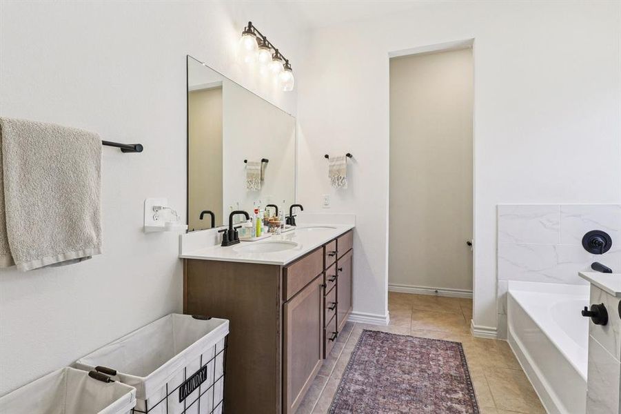 Full bathroom with a garden tub, double vanity, and light tile patterned floors Full bathroom with a garden tub, double vanity, and light tile patterned floors