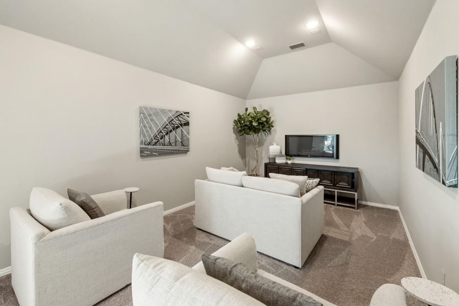 Living room with vaulted ceiling, gray carpet, white sofas, and wall-mounted TV on dark media console