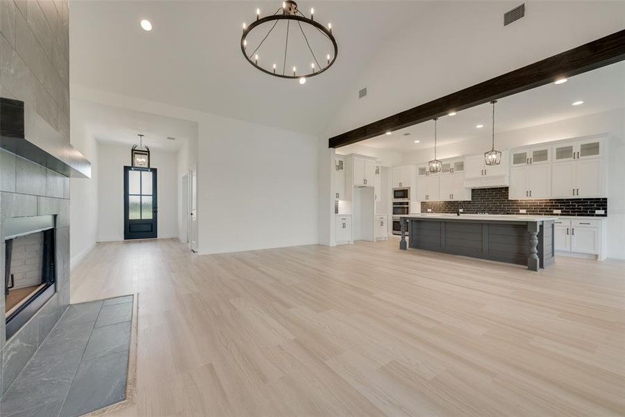 Unfurnished living room featuring a high ceiling, a fireplace, a chandelier, and light hardwood / wood-style flooring