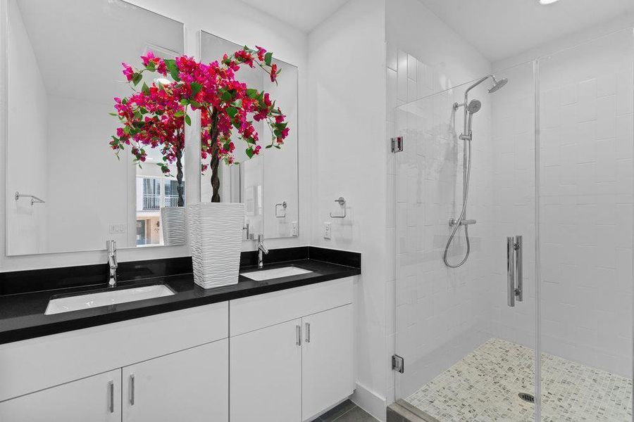 Bathroom featuring double vanity and a stall shower