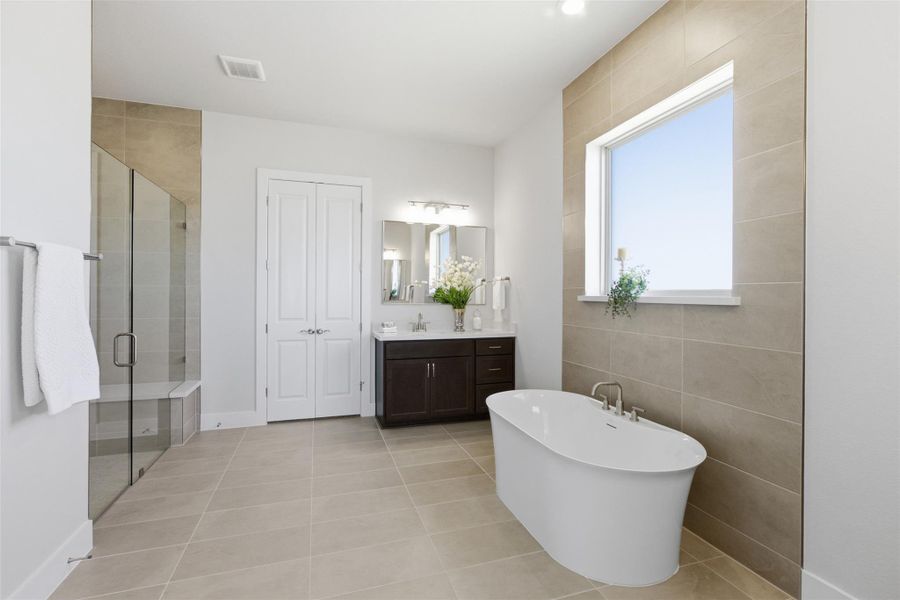 Bathroom with a freestanding tub, light tile patterned flooring, a stall shower, vanity, and tile walls