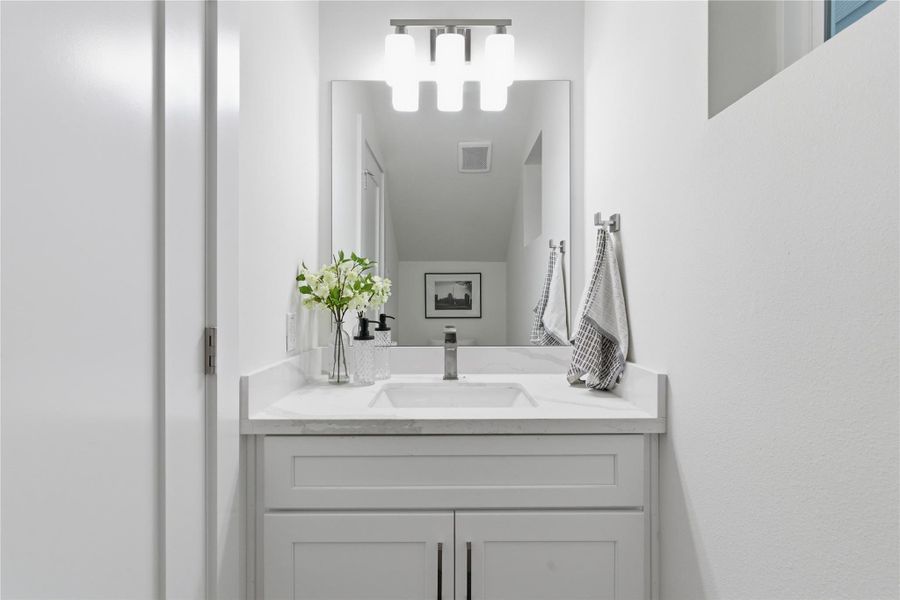 A sleek powder bath features a quartz vanity, modern fixtures, and clean finishes for a polished touch.