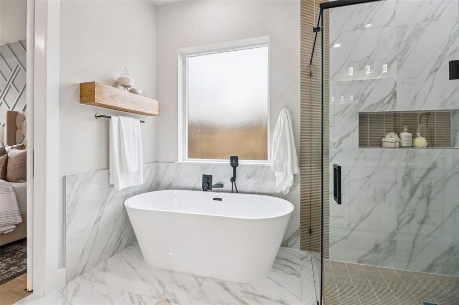 Bathroom with marble tiled floors, a marble finish shower, a soaking tub, connected bathroom, and tile walls