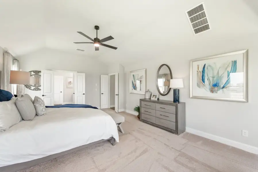 Master bedroom with vaulted ceiling, ceiling fan, gray dresser, and carpet flooring