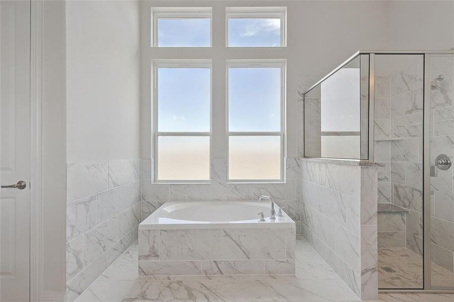 Bathroom with a marble finish shower, a garden tub, and marble look tile flooring Bathroom with a marble finish shower, a garden tub, and marble look tile flooring
