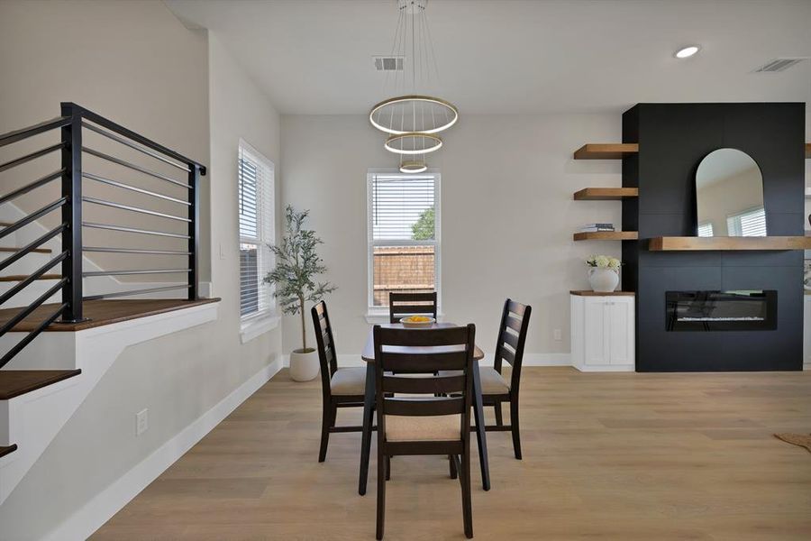 Dining room with light wood finished floors, a fireplace, baseboards, stairway, and recessed lighting Dining room with light wood finished floors, a fireplace, baseboards, stairway, and recessed lighting