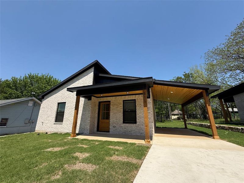 View of front of home with a front yard, brick siding, a carport, and driveway View of front of home with a front yard, brick siding, a carport, and driveway