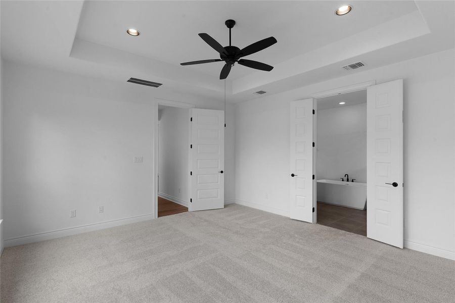 Unfurnished bedroom featuring a raised ceiling, recessed lighting, carpet floors, and ceiling fan