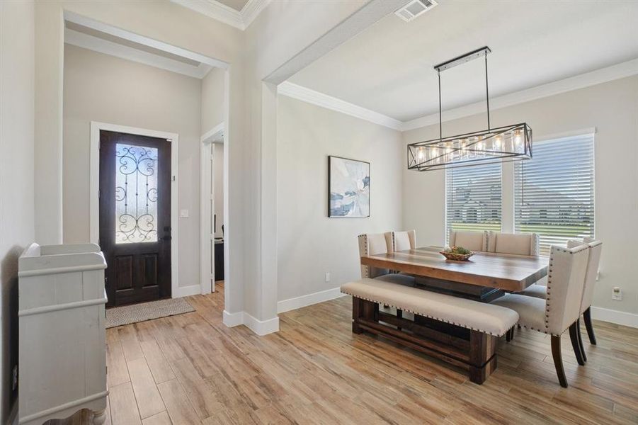 Dining room with light wood finished floors and crown molding