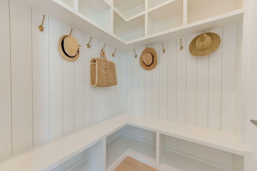 Charming drop zone adds both style and function with a built-in bench, wall paneling, overhead storage, and decorative hooks—an ideal landing spot for bags, jackets, and everyday essentials when coming and going. Charming drop zone adds both style and function with a built-in bench, wall paneling, overhead storage, and decorative hooks—an ideal landing spot for bags, jackets, and everyday essentials when coming and going.