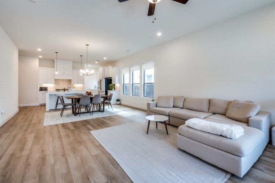 Living room with a chandelier, light wood finished floors, a ceiling fan, and recessed lighting Living room with a chandelier, light wood finished floors, a ceiling fan, and recessed lighting