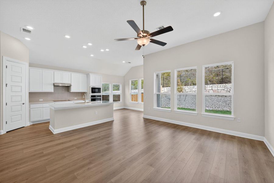 Kitchen featuring white cabinets, decorative backsplash, recessed lighting, a kitchen island with sink, and open floor plan Kitchen featuring white cabinets, decorative backsplash, recessed lighting, a kitchen island with sink, and open floor plan
