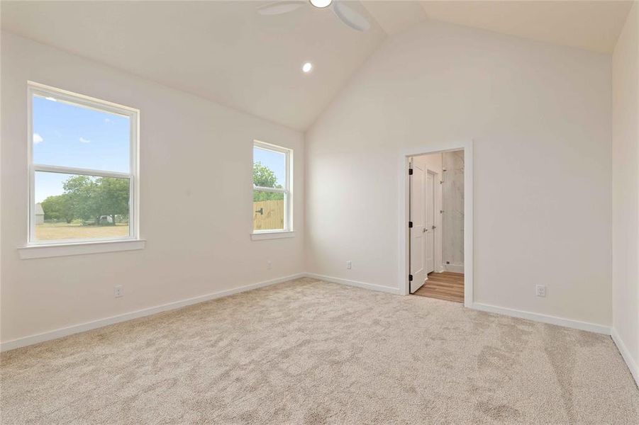 Unfurnished bedroom with light carpet, high vaulted ceiling, ceiling fan, recessed lighting, and connected bathroom Unfurnished bedroom with light carpet, high vaulted ceiling, ceiling fan, recessed lighting, and connected bathroom