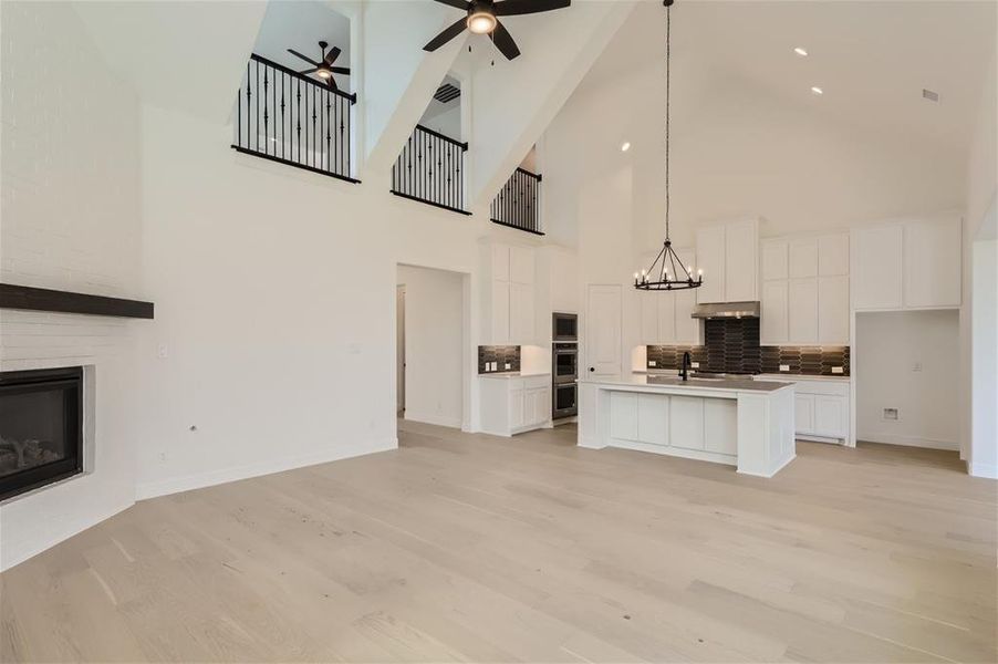 Kitchen with an island with sink, high vaulted ceiling, backsplash, and light wood-type flooring