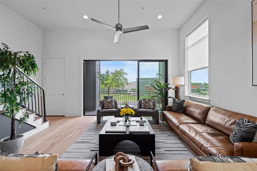 Living area featuring high ceilings, wood-finish flooring, a contemporary ceiling fan, and recessed lighting