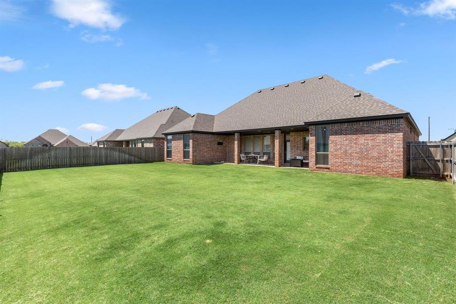 Back of property with brick siding, a shingled roof, a fenced backyard, and a patio area Back of property with brick siding, a shingled roof, a fenced backyard, and a patio area