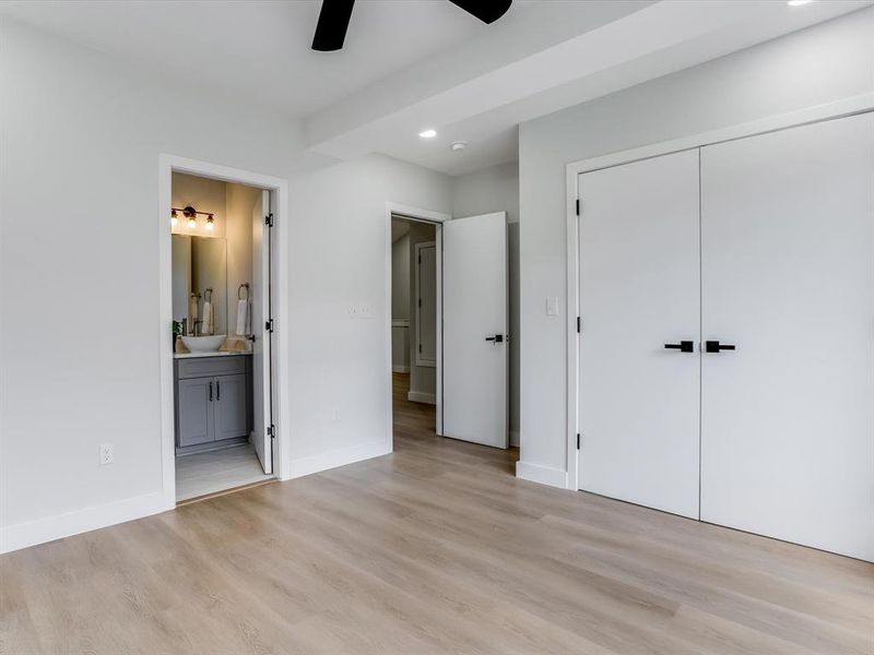 Upstairs guest bedroom featuring wood-finish flooring, recessed lighting, and a black ceiling fan Upstairs guest bedroom featuring wood-finish flooring, recessed lighting, and a black ceiling fan