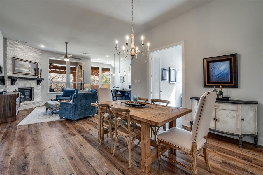 Dining area with a large fireplace, dark wood-type flooring, ceiling fan, and hanging lights