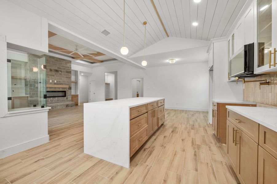 Kitchen with light stone counters, open floor plan, lofted ceiling, a kitchen island, and wooden ceiling Kitchen with light stone counters, open floor plan, lofted ceiling, a kitchen island, and wooden ceiling